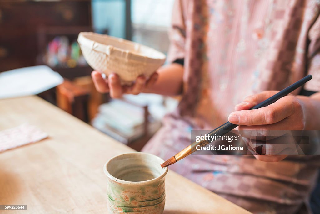 Craftsperson handpainting a paper bowl