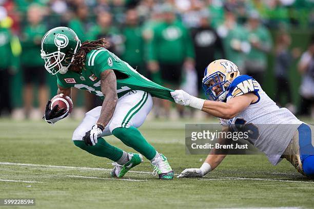 Taylor Loffler of the Winnipeg Blue Bombers grabs the jersey of Naaman Roosevelt of the Saskatchewan Roughriders trying to make a tackle in the game...