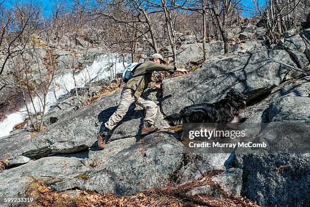 hiker scrambling for a hand hold on rocky pitch - murray mccomb stock pictures, royalty-free photos & images