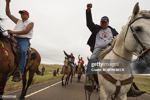 Native Americans ride with raised fists to a sacred burial ground that was disturbed by bulldozers building the Dakota Access Pipeline , near the...