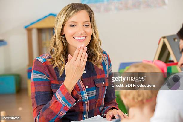 bonita maestra que usa el lenguaje de señas para hablar con el niño en edad preescolar - sign language fotografías e imágenes de stock
