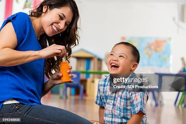 happy little boy with down syndrome playing with bubbles - bubbles happy stockfoto's en -beelden