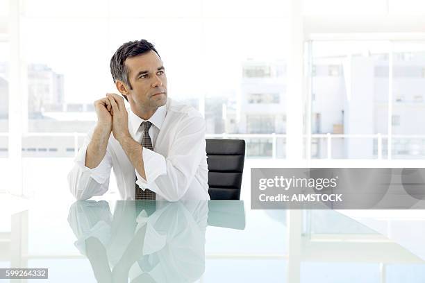 uomo d'affari pensieroso seduto in sala riunioni - cfo foto e immagini stock