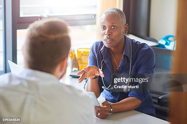 doctor chatting to male patient - allmänläkare bildbanksfoton och bilder