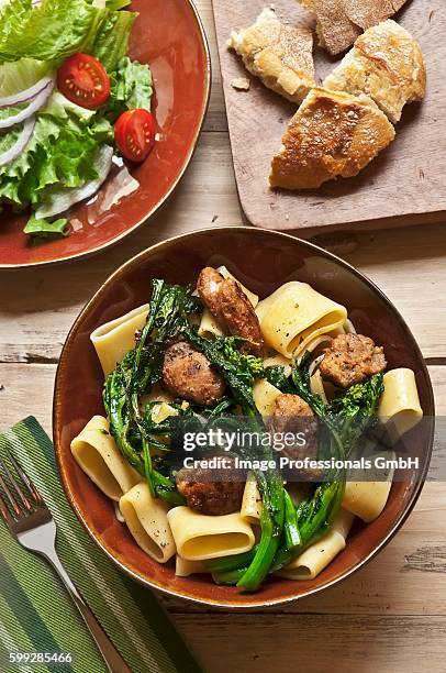 bowl of pasta with broccoli rabe and sausage; salad and bread - broccoli rabe fotografías e imágenes de stock