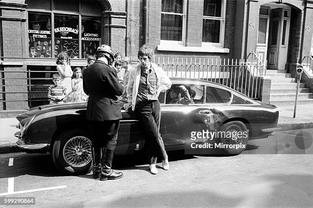 Jagger's Girlfriend Chrissie Shrimpton looks on as Mick has his particulars taken by a patrolman.