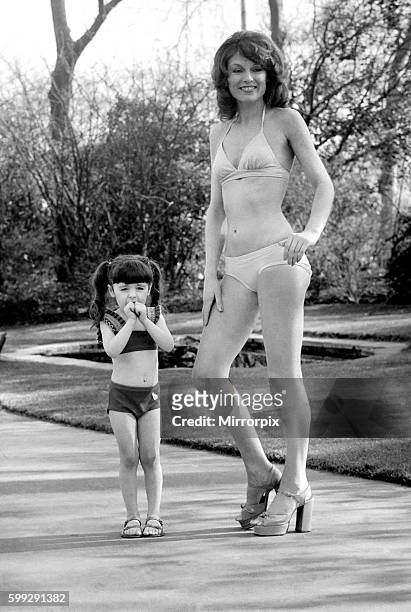 Woman wearing a bikini standing i n the park with a little girl February 1975 75-01132