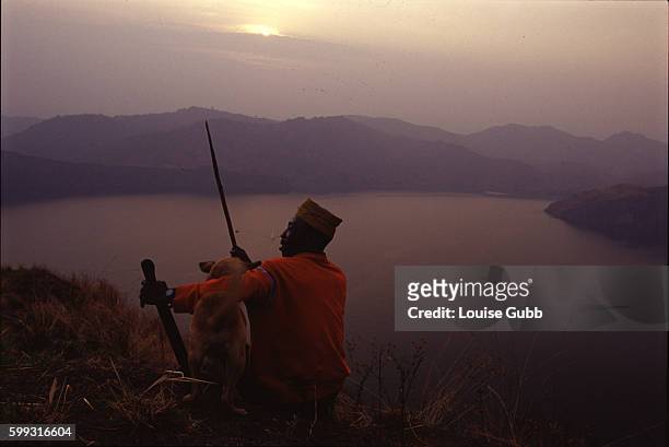 Villager Che Ephriam, one of the survivors of the 1986 carbon dioxide gas tragedy, sits with Gabon, his hunting dog. The gas asphyxiated 2000 people...