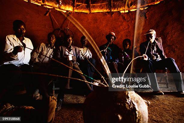 Group of Sabiny elders in Kapchorwa, Uganda, drink beer from a communal pot to celebrate a circumcision ceremony. While a traditional rite of passage...