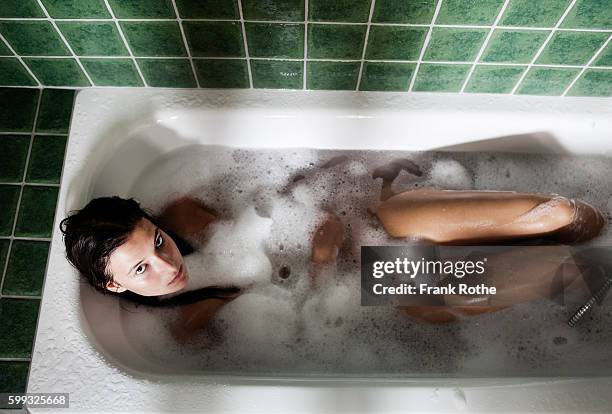 young woman enjoying bath in green bathroom - woman bath tub wet hair stock pictures, royalty-free photos & images