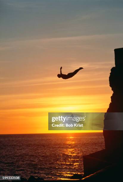 cliff diver above setting sun - salto desde acantilado fotografías e imágenes de stock