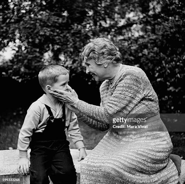 Teacher and author Helen Keller touches the face of a young boy. Keller achieved wide recognition by overcoming blindness and deafness to become a...
