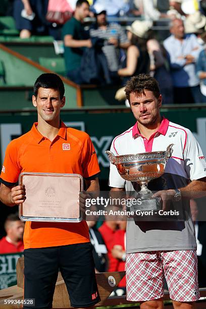 Stanislas Wawrinka of Switzerland holds the Coupe de Mousquetaires as he consoles runner up Novak Djokovic of Serbia after their Men's Singles Final...