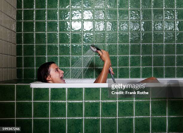 young woman singing in shower and bathtub in green bathroom - woman bath tub wet hair stock pictures, royalty-free photos & images