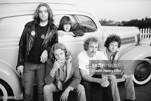 Members of The Eagles stand around a vintage car. Members are, clockwise, Glen Frey, Randy Meisner, Don Henley, Bernie Leadon, and Don Felder.
