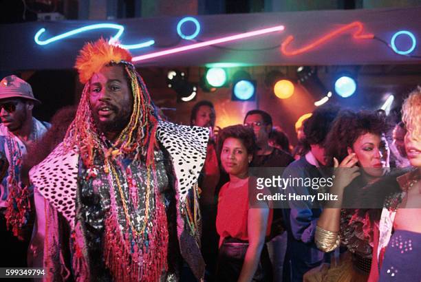 George Clinton stands on the dance floor of a discotheque on a music video shoot. George Clinton created pioneering funk bands Funkadelic and...