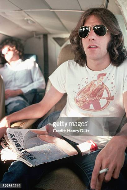 On the private jet to their next show, The Eagles' Glenn Frey smokes a cigarette and "reads" Playboy magazine. The Eagles were the most popular band...