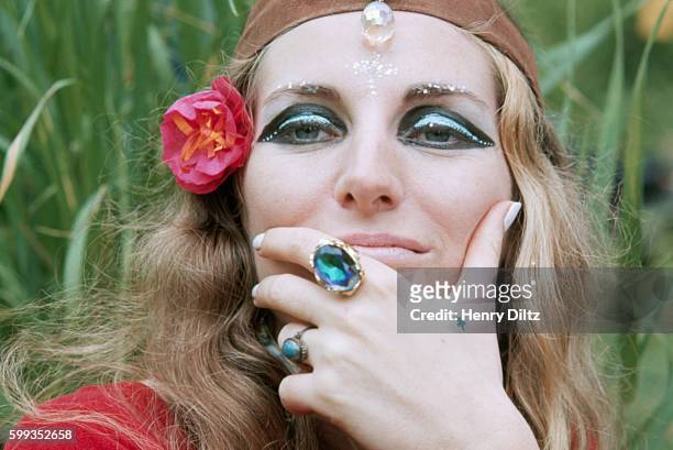 Woman at a sit-in wears typical hippie attire including crystal jewelry and scarf around her head. She is also wearing heavy eyeshadow.