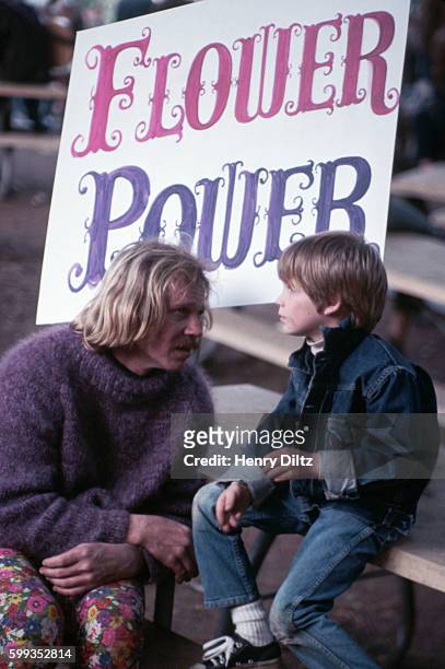 Singer Barry McGuire talks to a little boy and carries a "Flower Power" sign at a love-in. McGuire had one hit with "Eve of Destruction". Los...