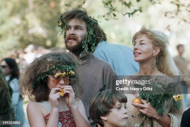 Hippie parents and their preteen children carry flowers at a Los Angeles love-in.