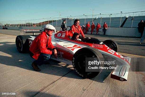 Paul Newman, actor and autoracer, crouches beside Mario Andretti's Formula One car at the Atlanta Raceway for the Atlanta International.