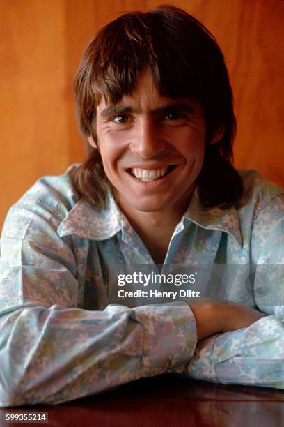 Davy Jones of The Monkees crosses his arms on a table.