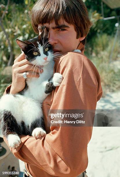 Davy Jones holds a black and white cat on the set of The Monkees TV show.