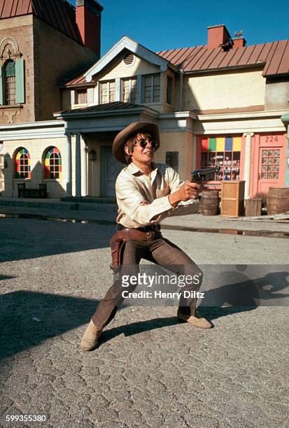 The Monkees' Davy Jones shoots a gun for a cowboy scene in the band's TV show.