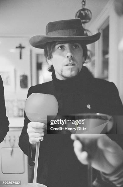 Musician Graham Nash of The Hollies has a drink from a very large champagne or wine glass.