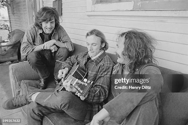 Musicians Graham Nash , Stephen Stills and David Crosby on a couch outside a house.