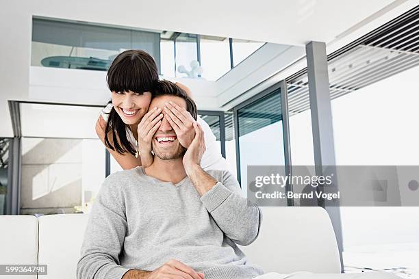 playful woman with hands over boyfriend's eyes - veralbern stock-fotos und bilder