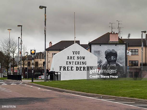 sign entering free derry with mural by bogside artists on side of house in derry, northern ireland - mural fotografías e imágenes de stock
