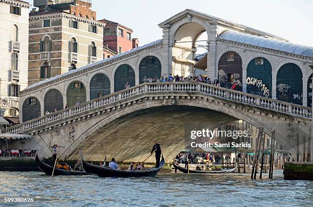 rialto bridge on the grand canal, venice, italy, europe with gondolas beneath - rialto bridge stock pictures, royalty-free photos & images