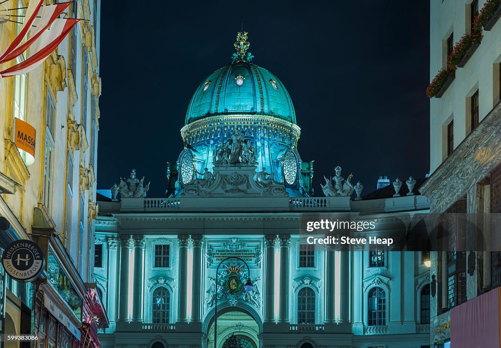 Dome of Hofburg Palace at night illuminated in blue with shops on Kohlmarkt framing view in Vienna, Austria