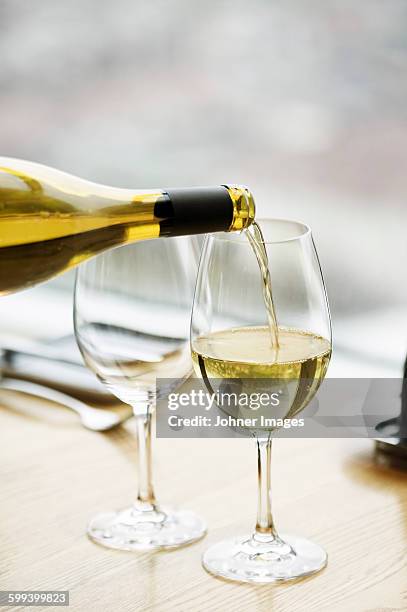 white wine is pouring into wineglass - white wine stockfoto's en -beelden