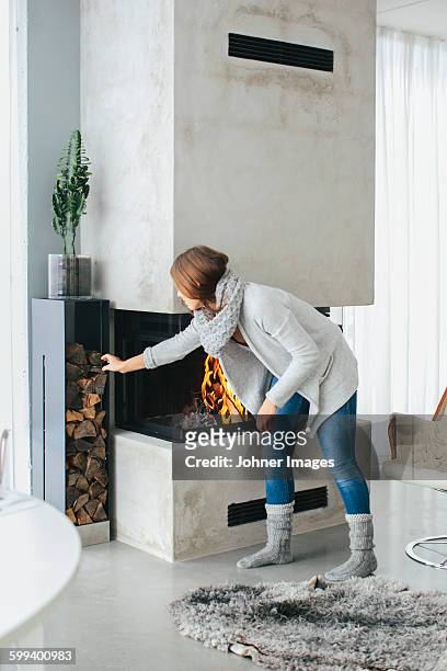 woman putting firewood in fireplace - johner images bildbanksfoton och bilder