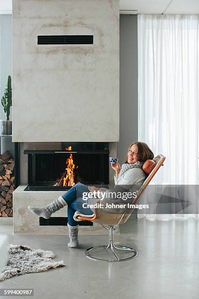 woman drinking coffee in front of fireplace - sheepskin stock pictures, royalty-free photos & images