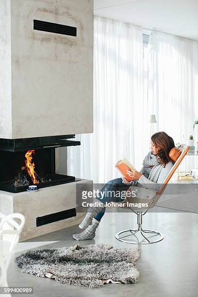woman reading book in front of fireplace - sheepskin stock pictures, royalty-free photos & images