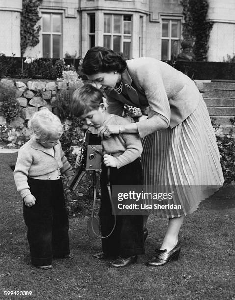 Queen Elizabeth II helps her son Prince Charles to take a picture of his sister, Princess Anne, Balmoral, Scotland, 1952.