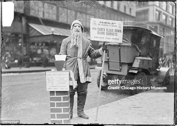 Image of a man dressed up as Santa Claus holding a sign that reads, Help the Volunteers of America to send Santa down 10,000 chimneys of Chicago's...