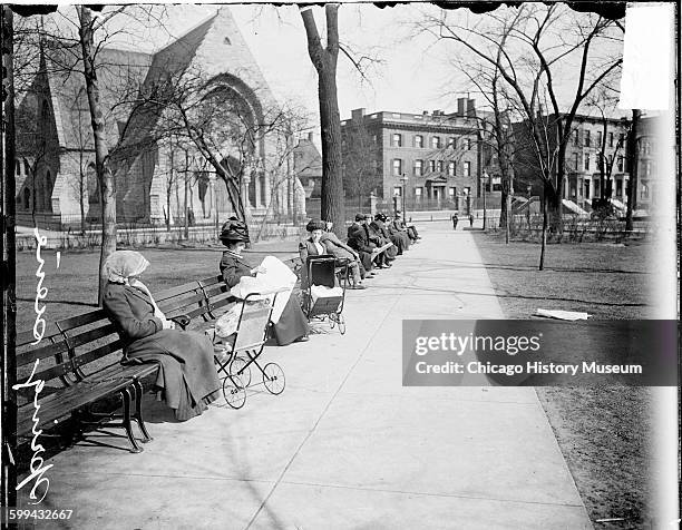 Image of people sitting on benches along a pathway through Washington Square Park in Spring in the Near North Side community area, Chicago, Illinois,...