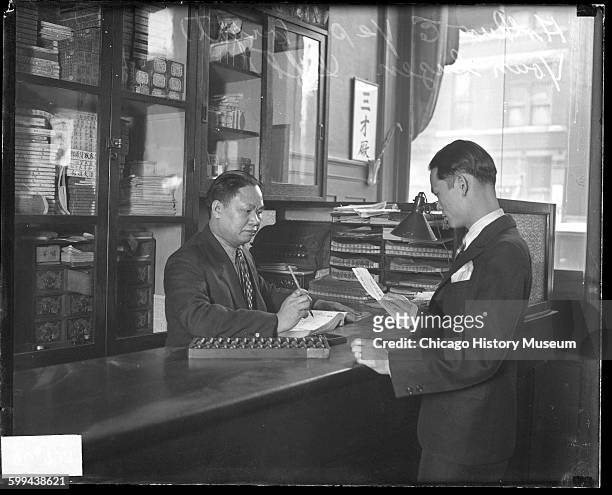 Youn Suzen and Arthur E Yip transact business in Chinatown, Chicago, Illinois, twentieth century.