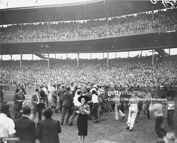 Crowd of fans, reporters, ushers, and players escorting Chicago Cubs baseball player Gabby Hartnett across home plate after his walk-off home run in...
