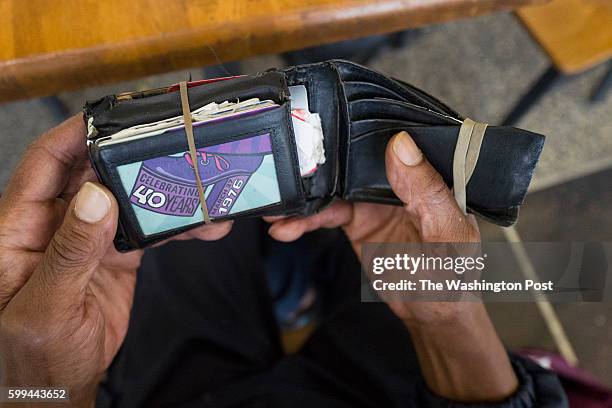 Charles Wells who earns the minimum wage with his job at Ronald Reagan Washington National Airport shows off his weathered wallet before starting his...