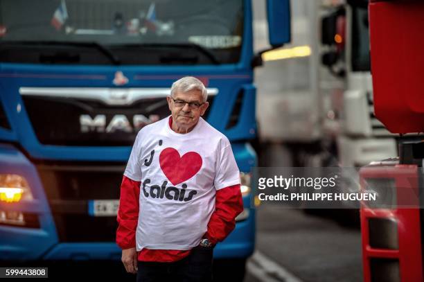 Man wearing a T-shirt reading "I love Calais" stands among trucks as a dozen of truck drivers gather in a parking on September 5, 2016 in Loon Plage...