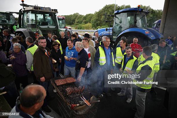 French farmers cook on a barbecue during their blockade of the main A16 motorway into the Channel Tunnel terminal protesting against the Jungle...