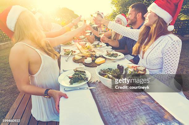 group of people toasting with santa hats. - summer christmas stock pictures, royalty-free photos & images