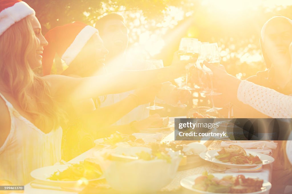 Group of people toasting with Santa hats.