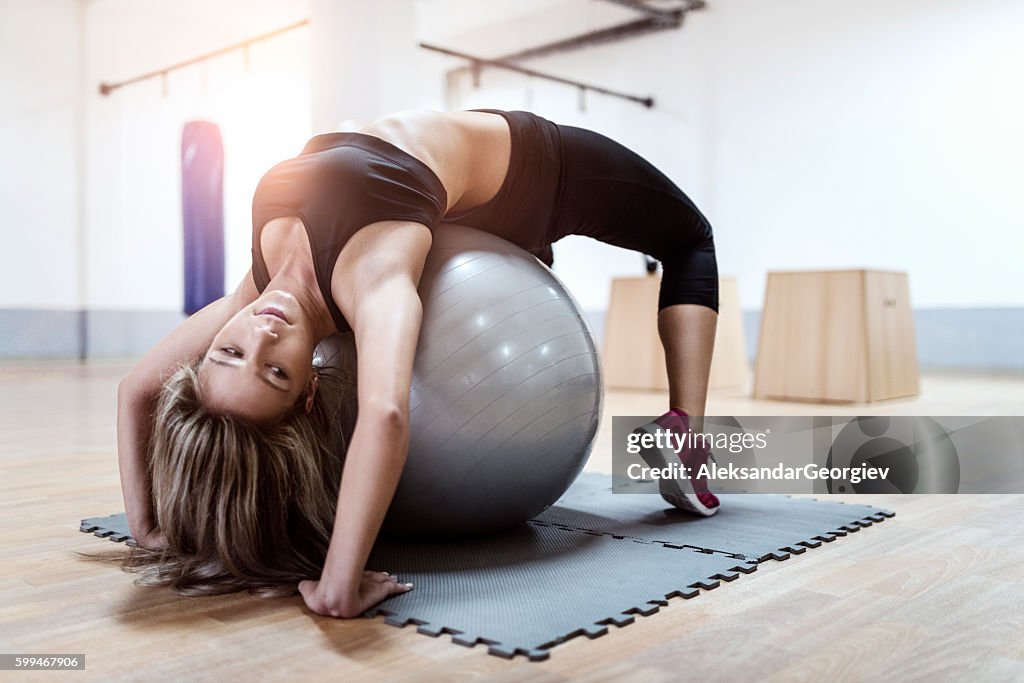 Young Woman Doing Backbend on Fitness Ball in Gym