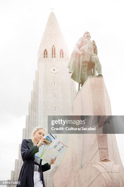 low angle view of teenage girl looking at map next to statue, hallgrmskirkja, reykjavik, iceland - hallgrimskirkja stock pictures, royalty-free photos & images